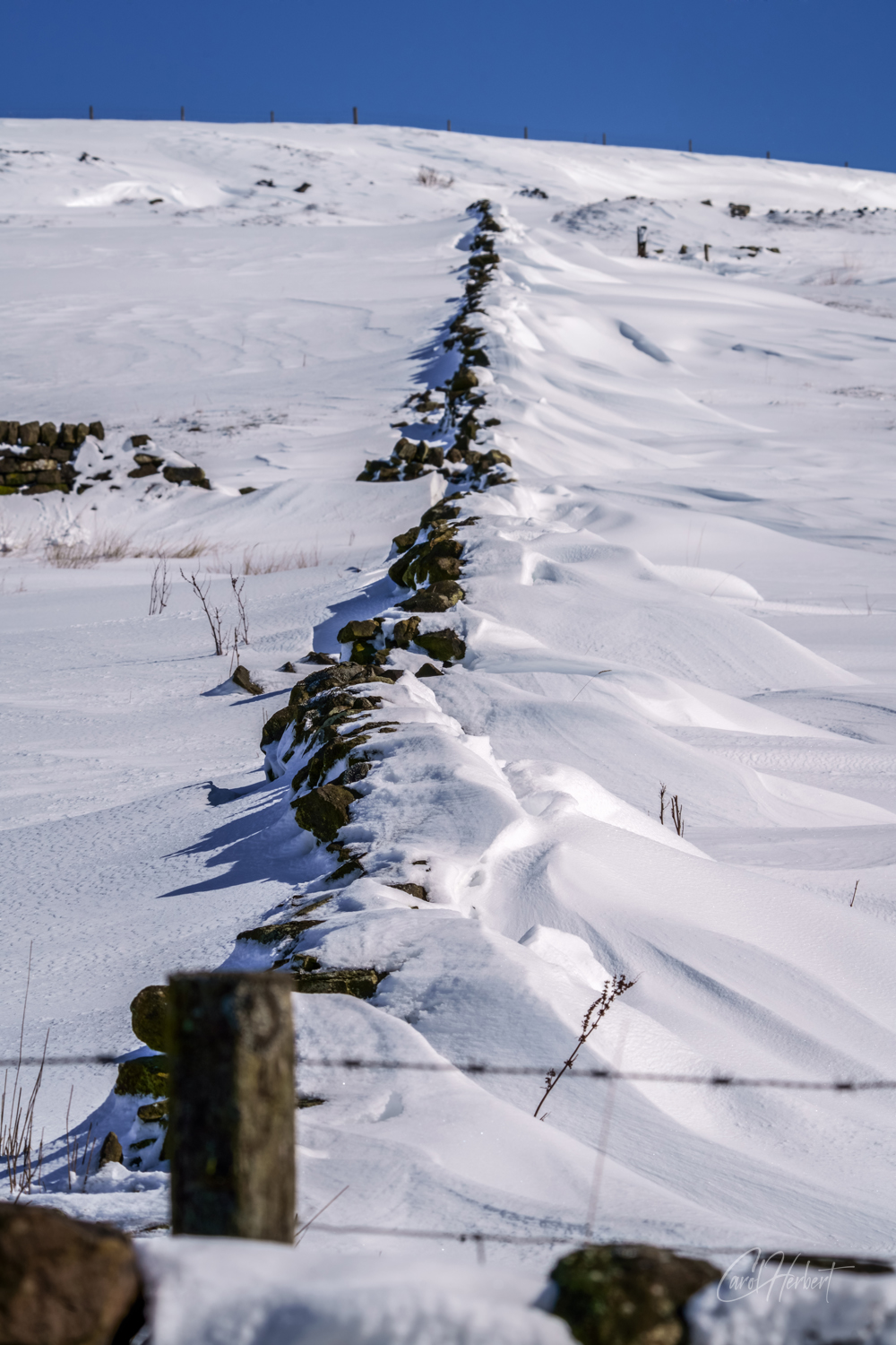 Snow drifting against a stone wall