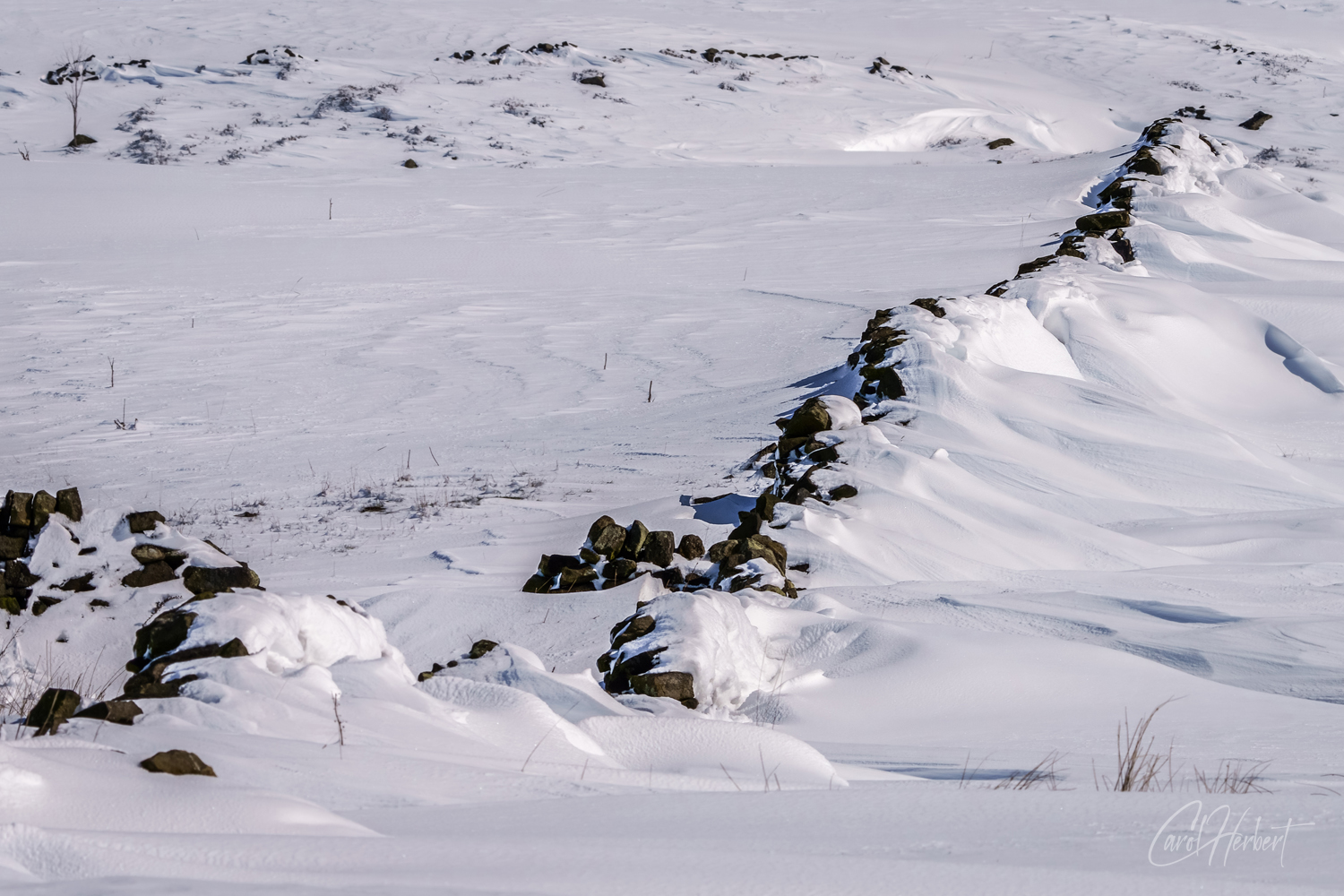 Snow drifting against a stone wall